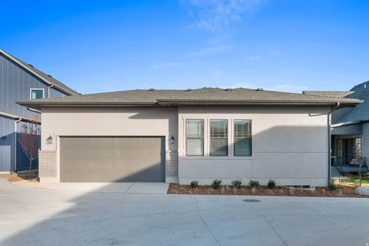 Exterior featuring a two-car garage with a panel door, decorative sconces, and a concrete driveway