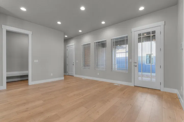 Spacious room featuring light wood-finish flooring, recessed lighting, and light gray wall tones