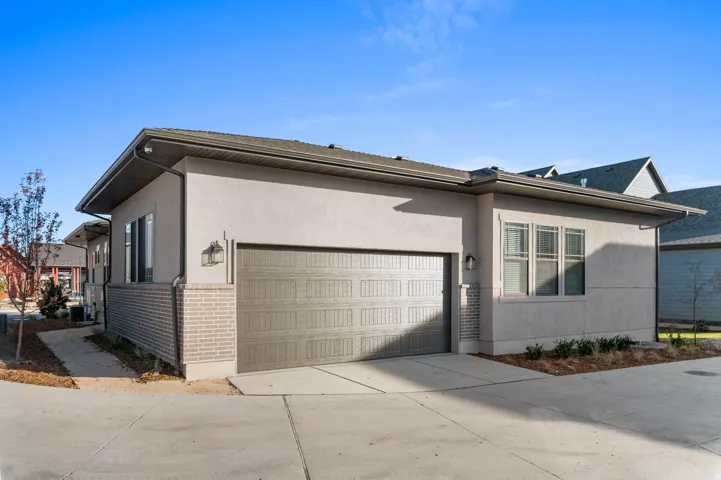 Exterior featuring stucco siding, a two-car garage with an overhead door, and a brick wainscot