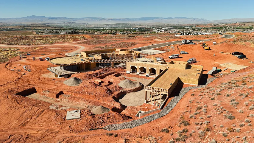Terraced hillside property with active construction, multiple building foundations, and partial roof framing
