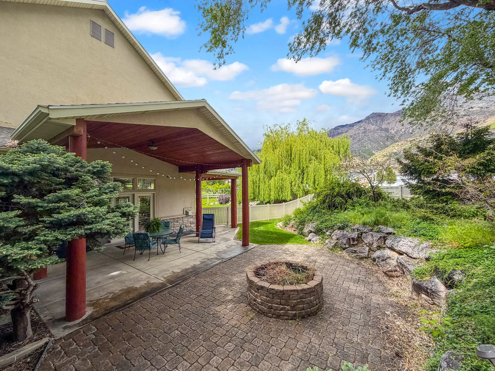 Expansive backyard featuring a covered patio, paved patio, and built-in fire pit