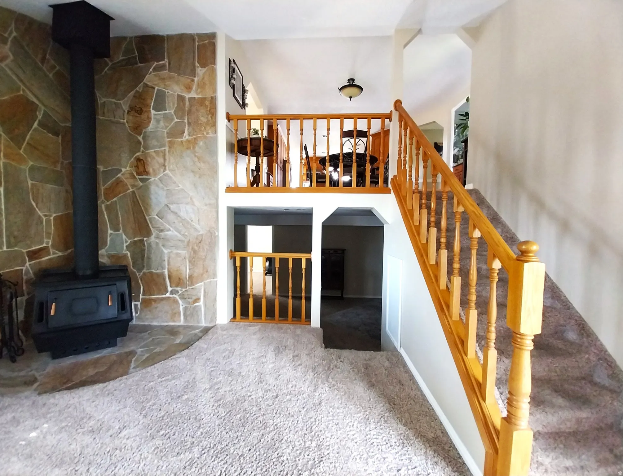 Living room featuring a wood stove, ceiling fan, and carpet flooring