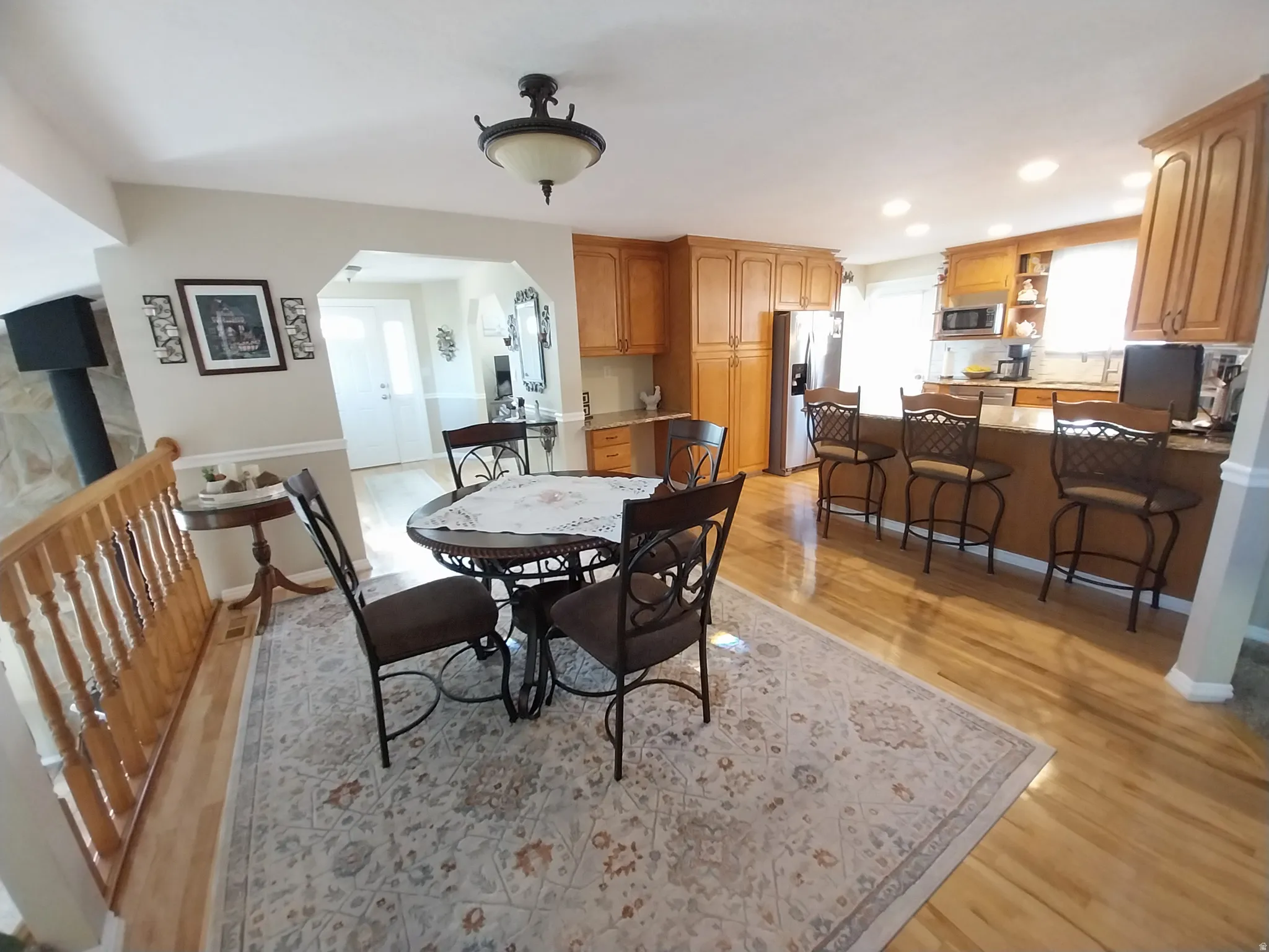 Dining room featuring light wood-style floors, arched walkways, and recessed lighting