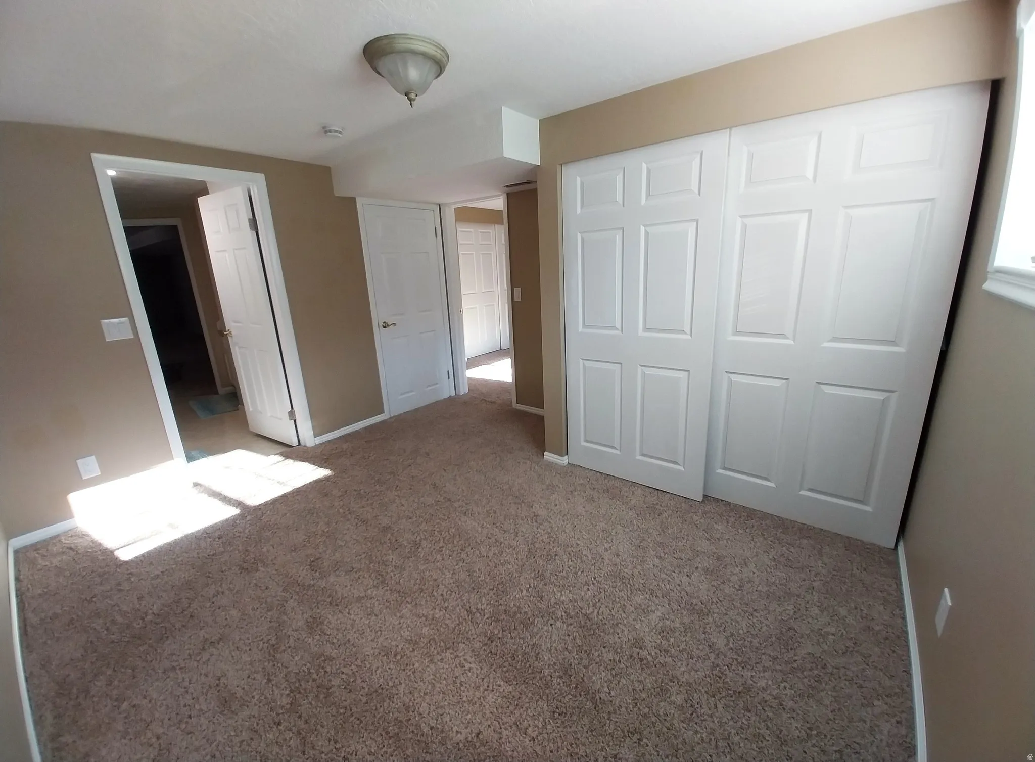 Unfurnished bedroom with light carpet and a closet