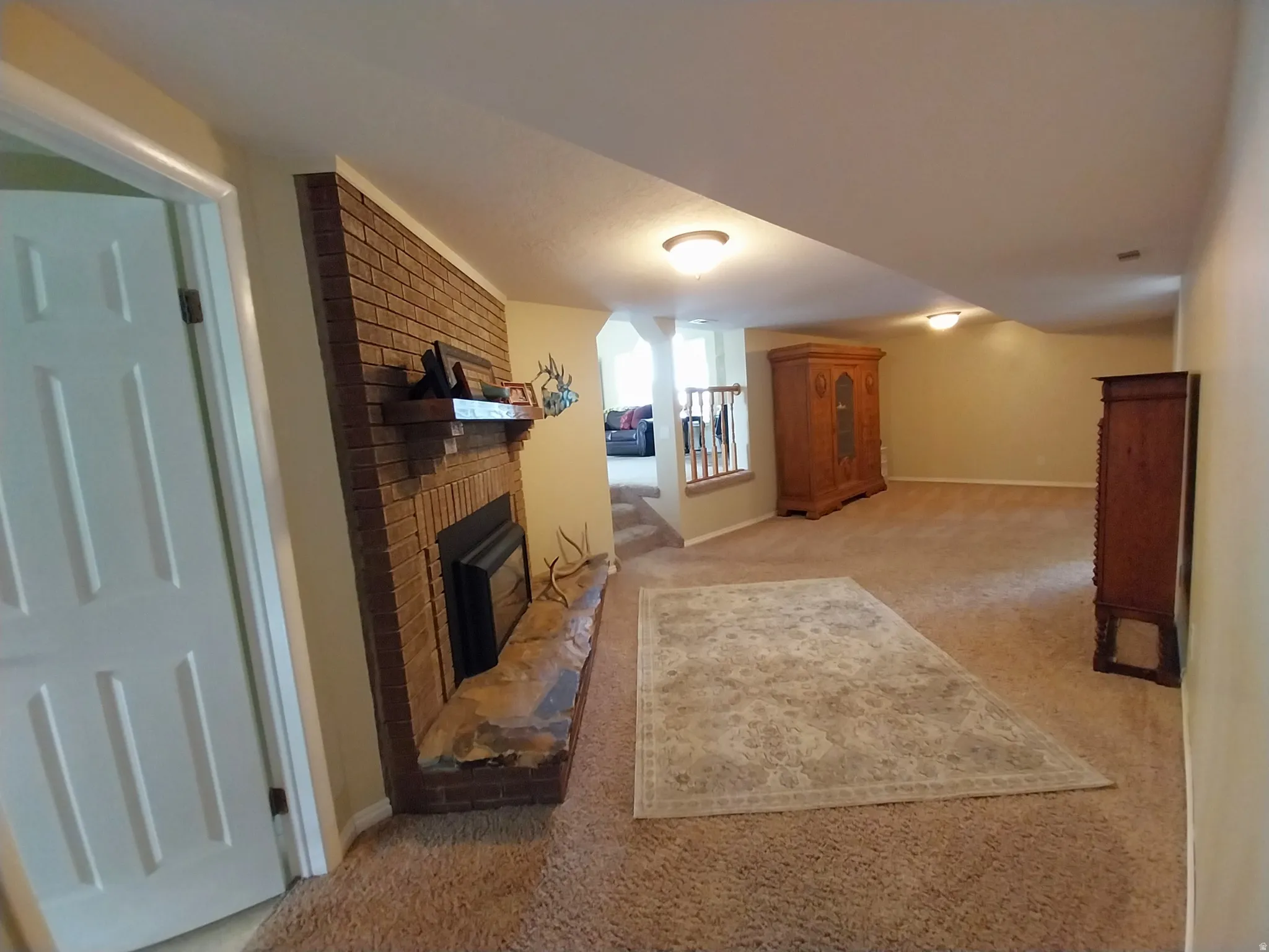 Living area with light carpet and a brick fireplace