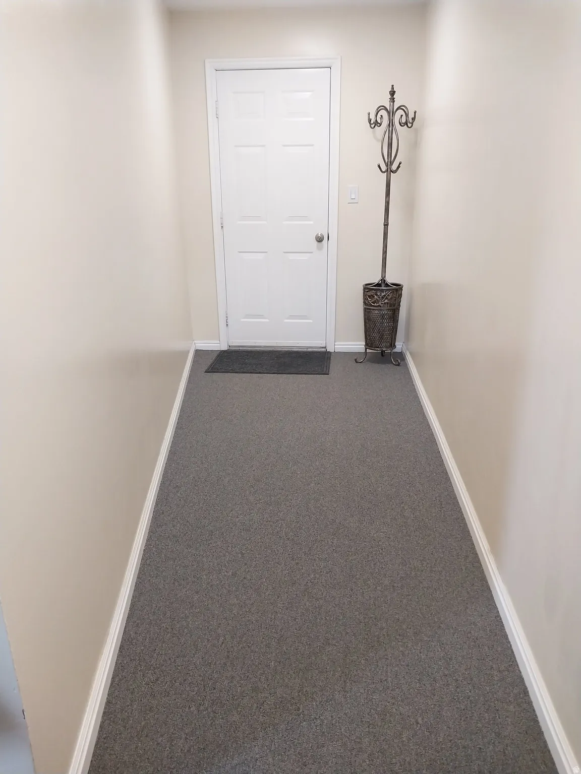 Garage hallway with gray carpet and baseboards