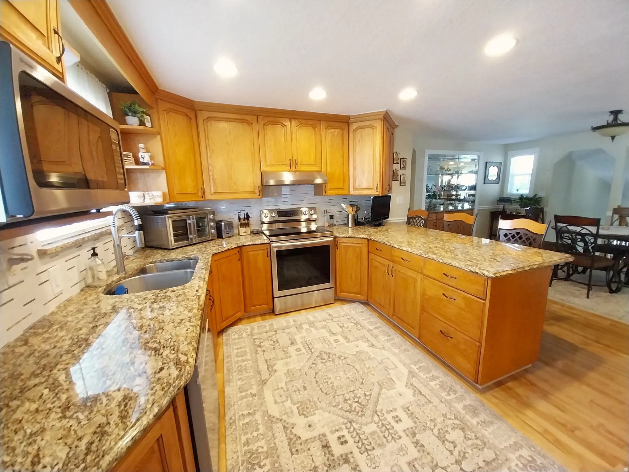 U-shaped kitchen featuring wood cabinetry, granite countertops, stainless steel appliances, and recessed lighting