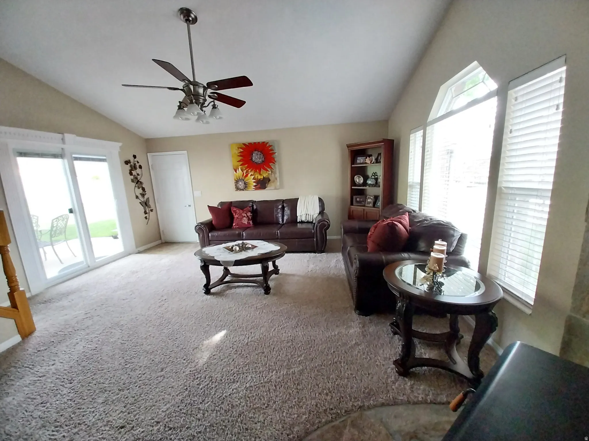 Living room featuring vaulted ceiling, carpet floors, plenty of natural light, and ceiling fan
