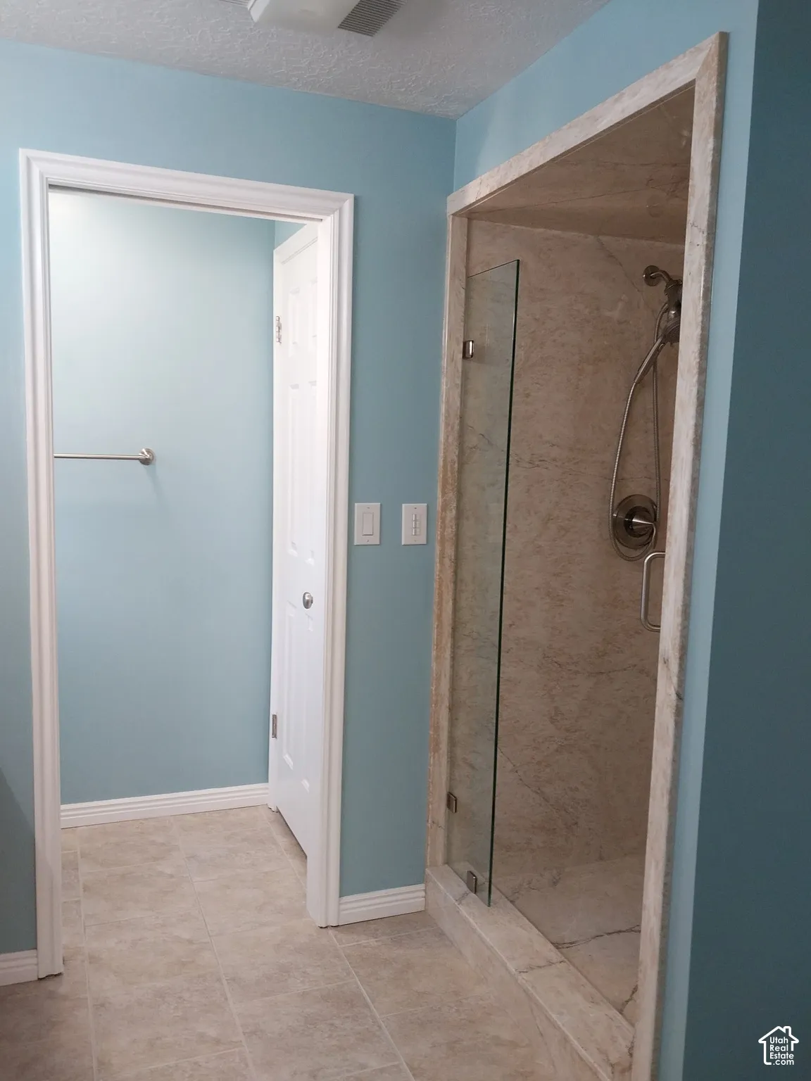 Tile flooring throughout, glass-enclosed shower with tile surround, and a ceiling-mounted light fixture