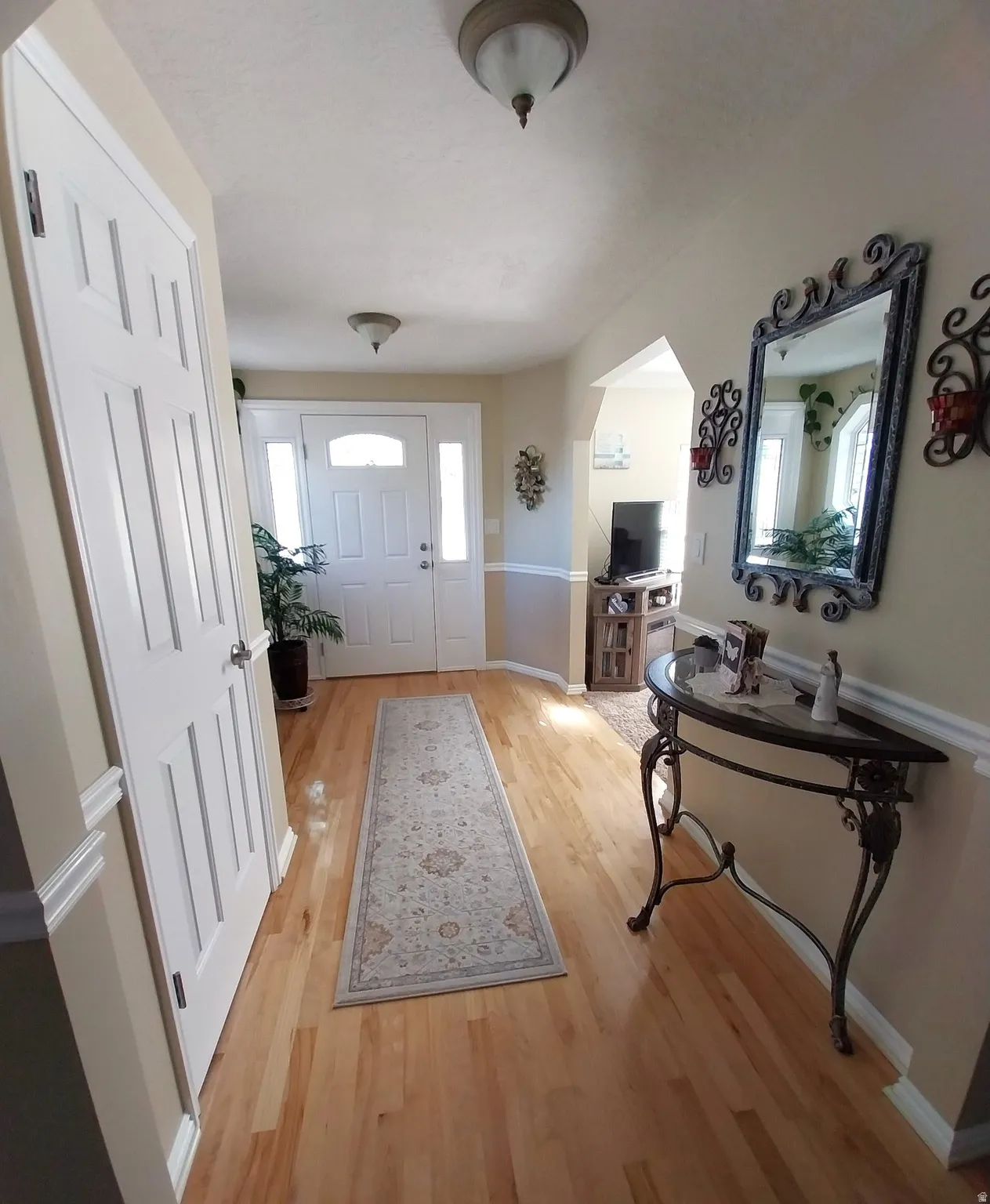 Entrance foyer with arched walkways and light wood finished floors