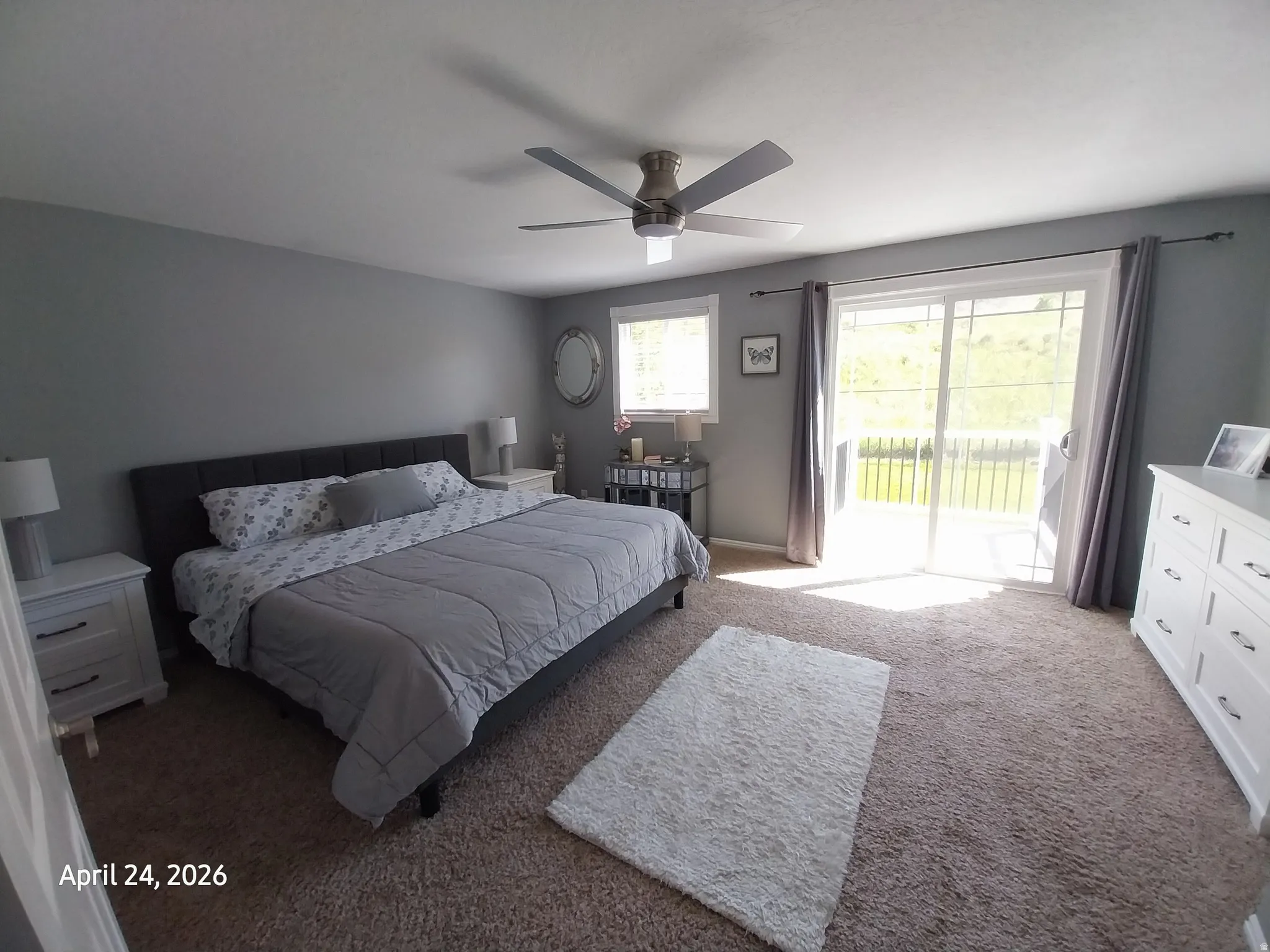 Master bedroom featuring light carpet, a ceiling fan, and access to exterior