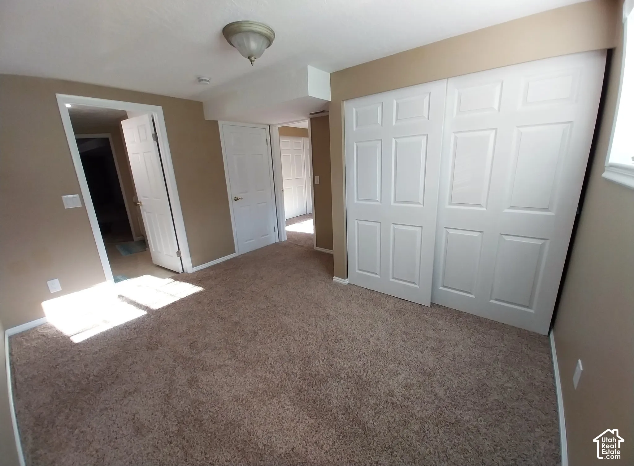 Unfurnished bedroom with light carpet and a closet