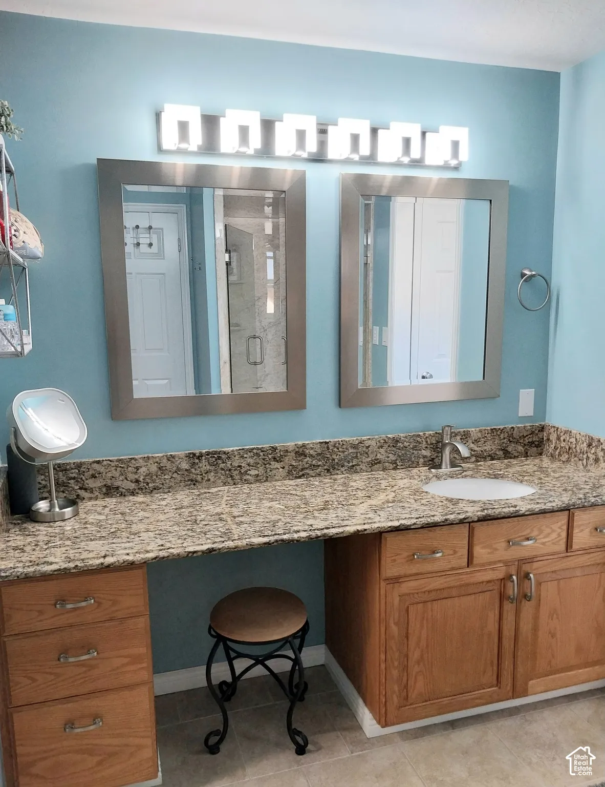 Dual framed vanity mirrors, natural stone-finish countertop, wood-finish cabinetry, and a single undermount sink