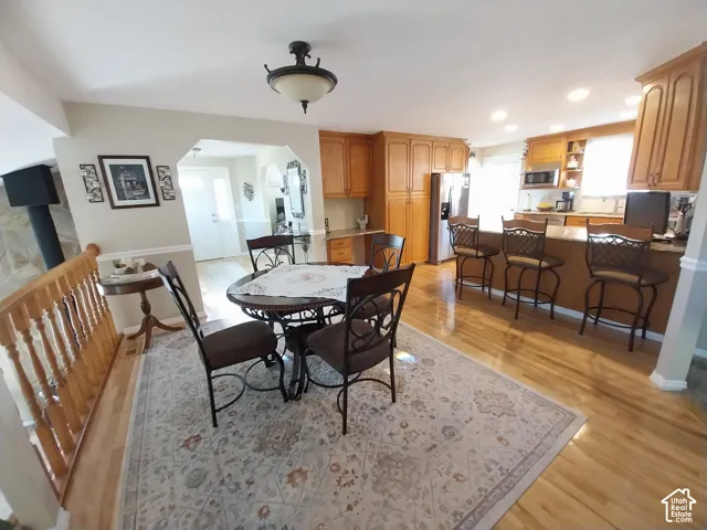 Dining room featuring light wood-style floors, arched walkways, and recessed lighting