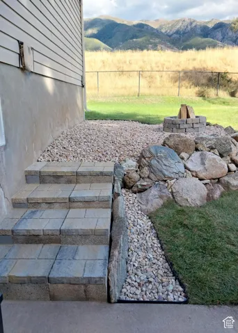 Exterior featuring a stone paver staircase, decorative rock landscaping, and a built-in stone fire pit