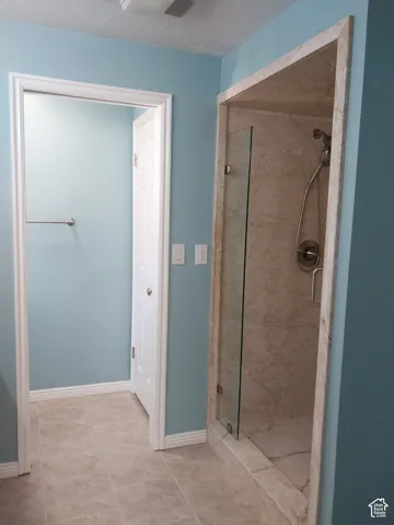 Tile flooring throughout, glass-enclosed shower with tile surround, and a ceiling-mounted light fixture