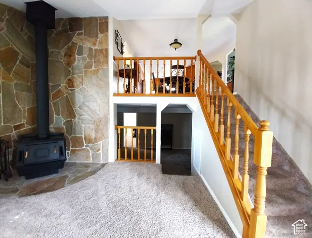 Living room featuring a wood stove, ceiling fan, and carpet flooring