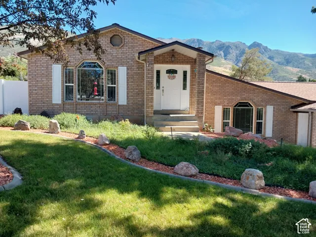 Brick exterior with white decorative shutters, a covered entry, and a multi-pane front door