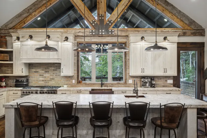 Kitchen featuring a large central island, exposed wood beams, and a brick backsplash