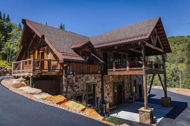 Rustic-modern residence featuring a stone and wood facade, a covered carport, and multiple balconies