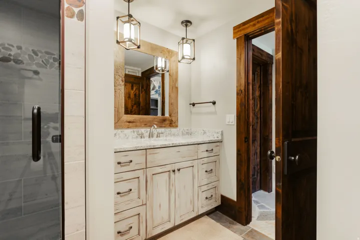 Whitewashed vanity with a light-toned countertop and dual pendant lighting fixtures