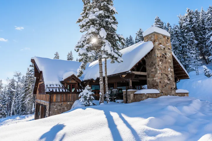 Stone and wood-clad exterior with a prominent stone chimney, A-frame roofline, and dormer windows