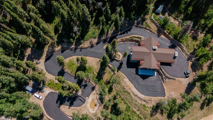 Expansive paved driveway leading to a multi-wing residence with a distinct brown shingle roof