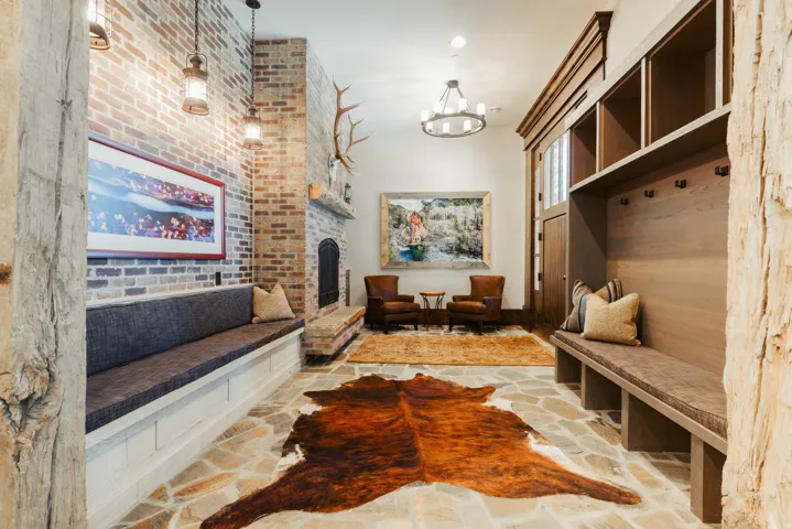 Stone flooring, exposed brick wall, built-in bench seating, wood-finish built-in storage, and a stone fireplace