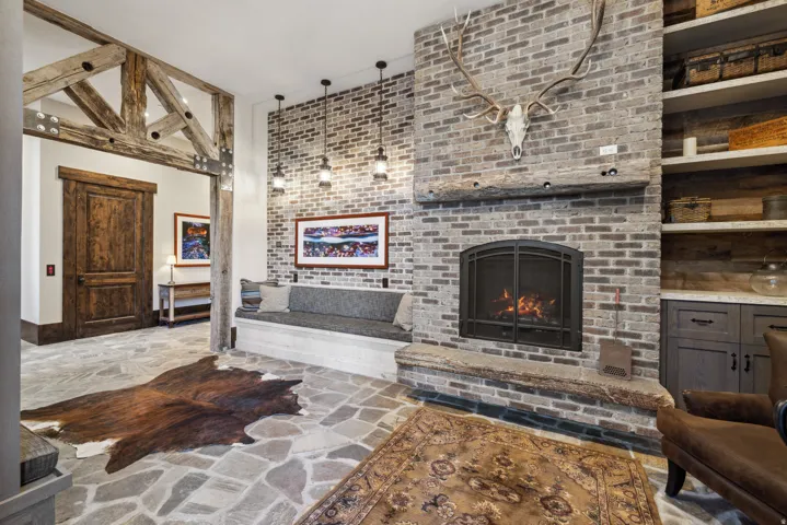 Stone flooring with a large brick fireplace featuring a hearth