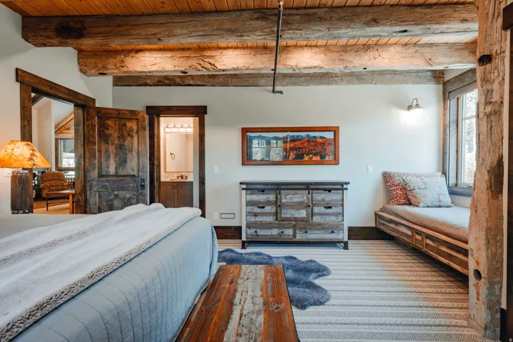 Exposed wood beam ceiling, wood-paneled ceiling, built-in window seating, distressed wood doors, wall-mounted lighting fixture