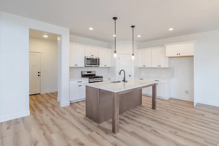 Kitchen featuring a wood-finish island with stone countertop, stainless steel appliances, white cabinetry, and wood-finish flooring