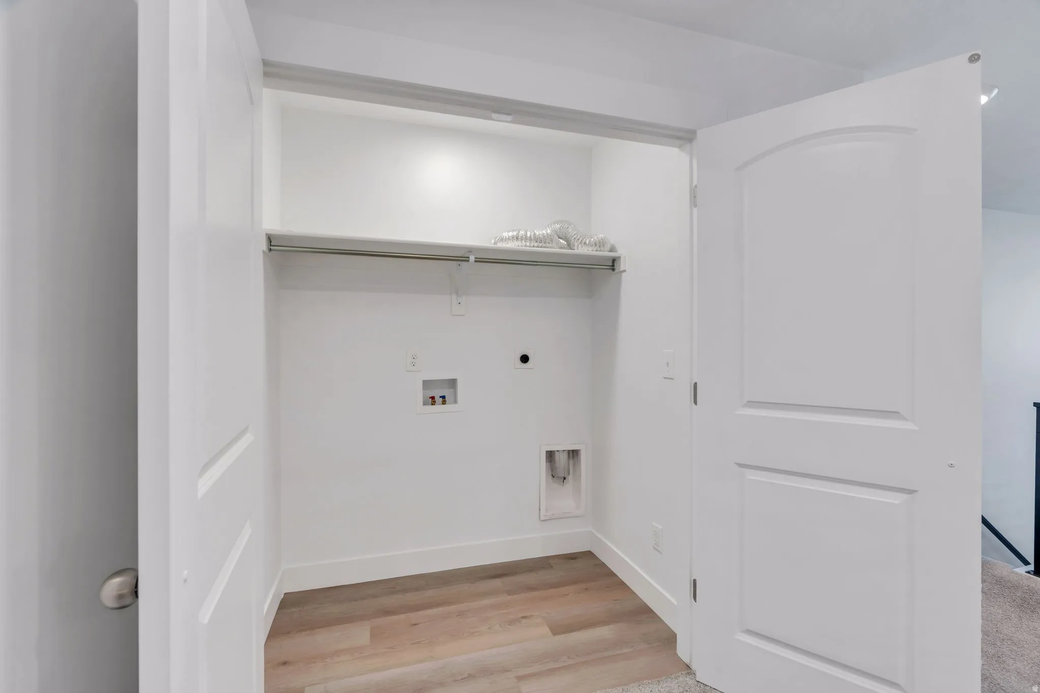 Dedicated laundry closet featuring a built-in shelf, clothing rod, and wood-finish flooring