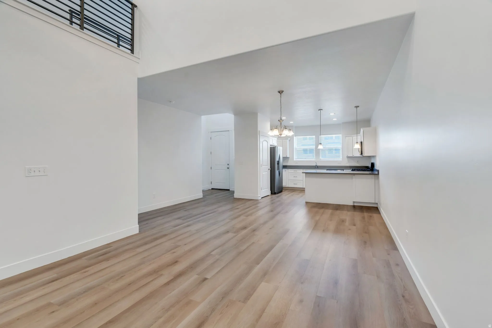 Open-concept living space featuring wood-finish flooring, white walls, and a modern kitchen