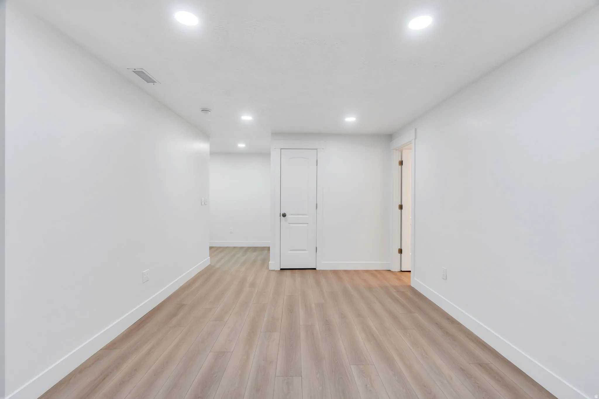 Open concept room featuring recessed lighting, wood-finish flooring, white walls, and bright white trim
