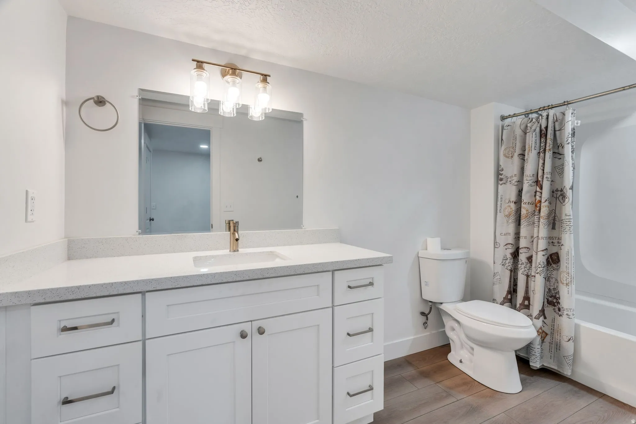 Bathroom featuring a spacious white vanity with a light speckled countertop, undermount sink, and gold-finish faucet
