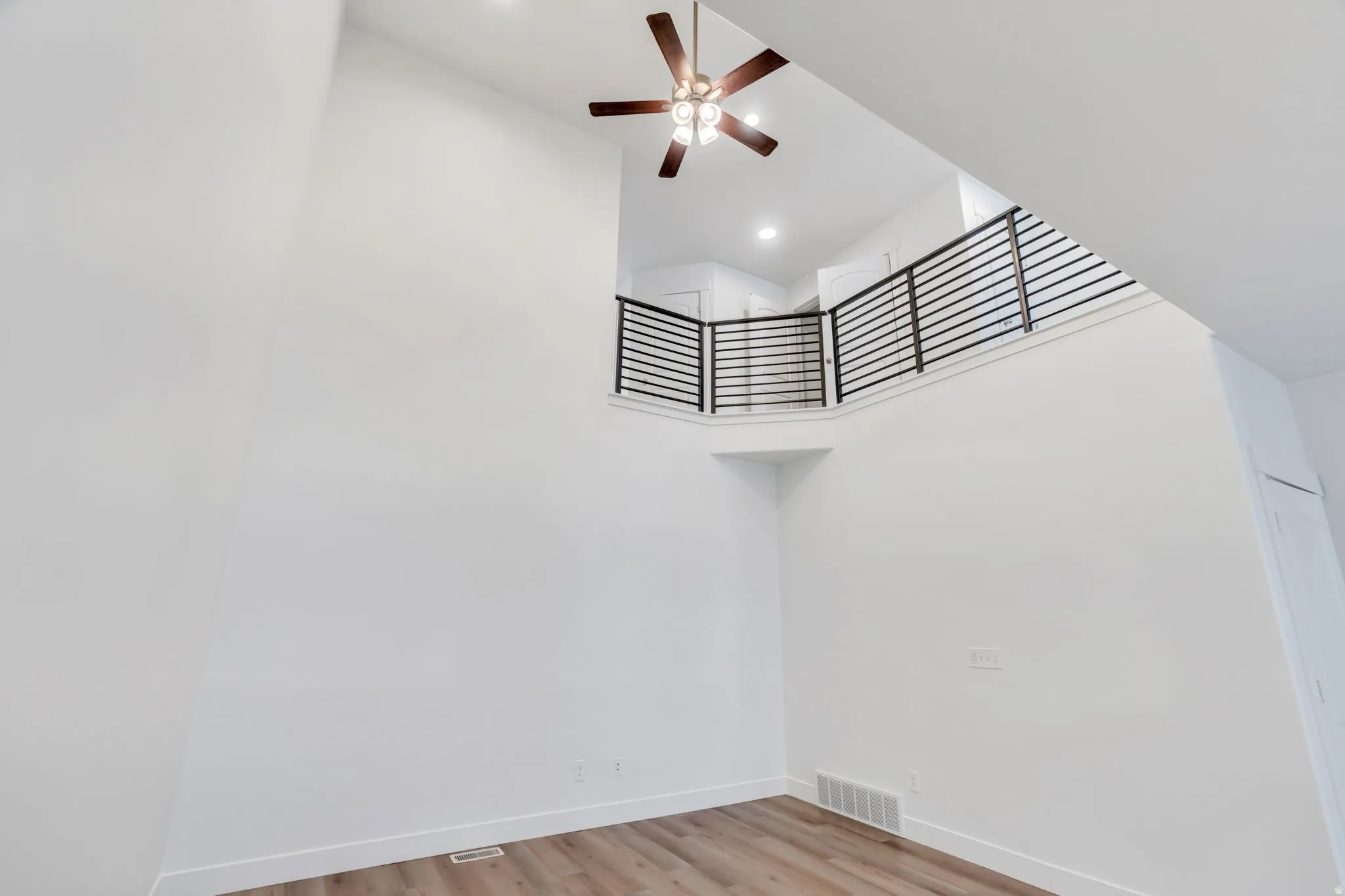 Two-story living area featuring a vaulted ceiling and a ceiling fan with integrated lighting