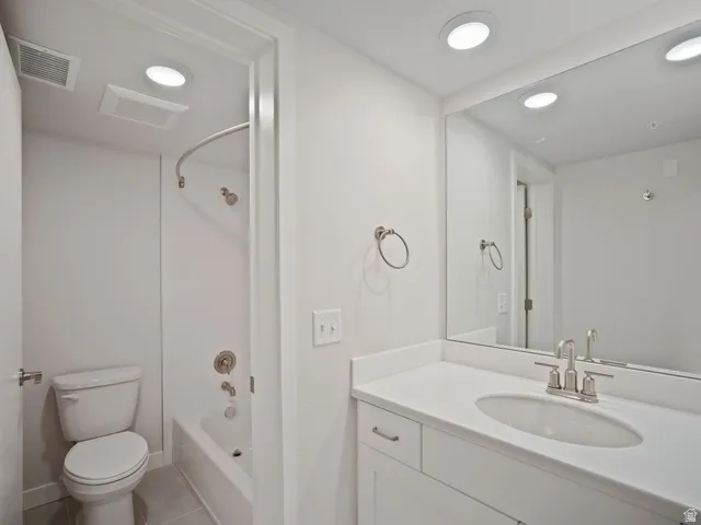 Bathroom featuring a white vanity with an integrated sink and brushed nickel faucet, a large wall-mounted mirror, and a white bathtub with a shower and brushed nickel fixtures