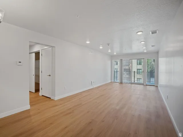 Spacious interior featuring wood-finish flooring, recessed lighting, and a private balcony with sliding glass doors