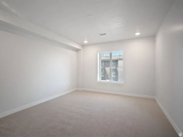 Recessed lighting illuminates neutral carpeting and white walls