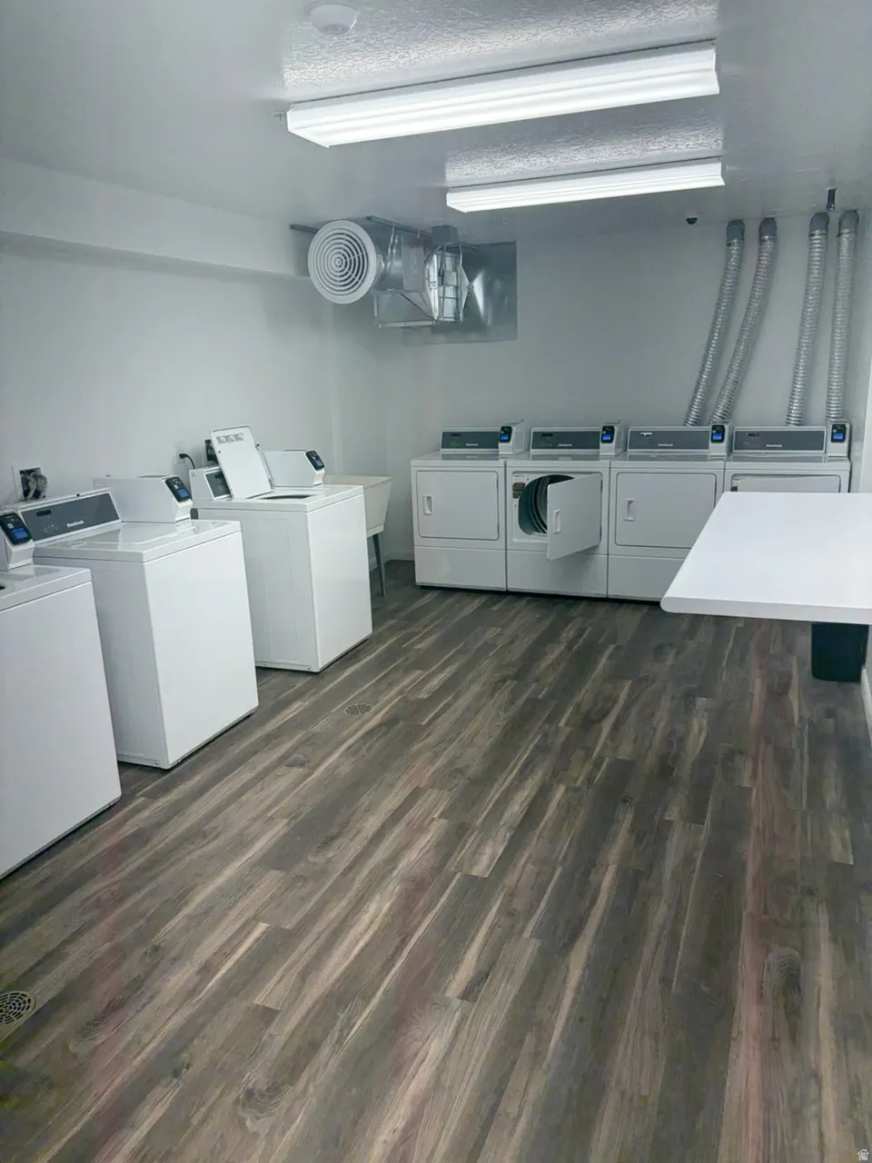 Dedicated laundry room featuring wood-finish flooring