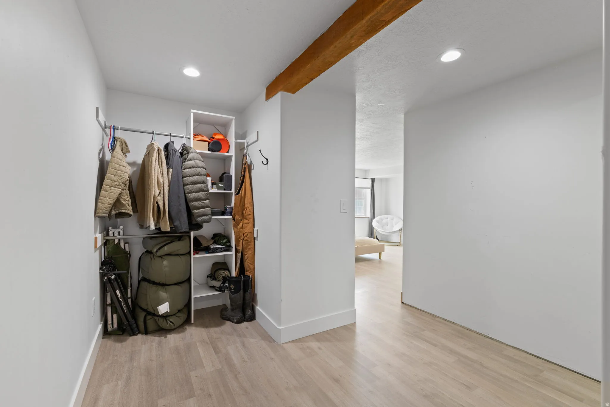 Entryway featuring wood-finish flooring, recessed lighting, and a built-in storage system with hanging rods and shelving
