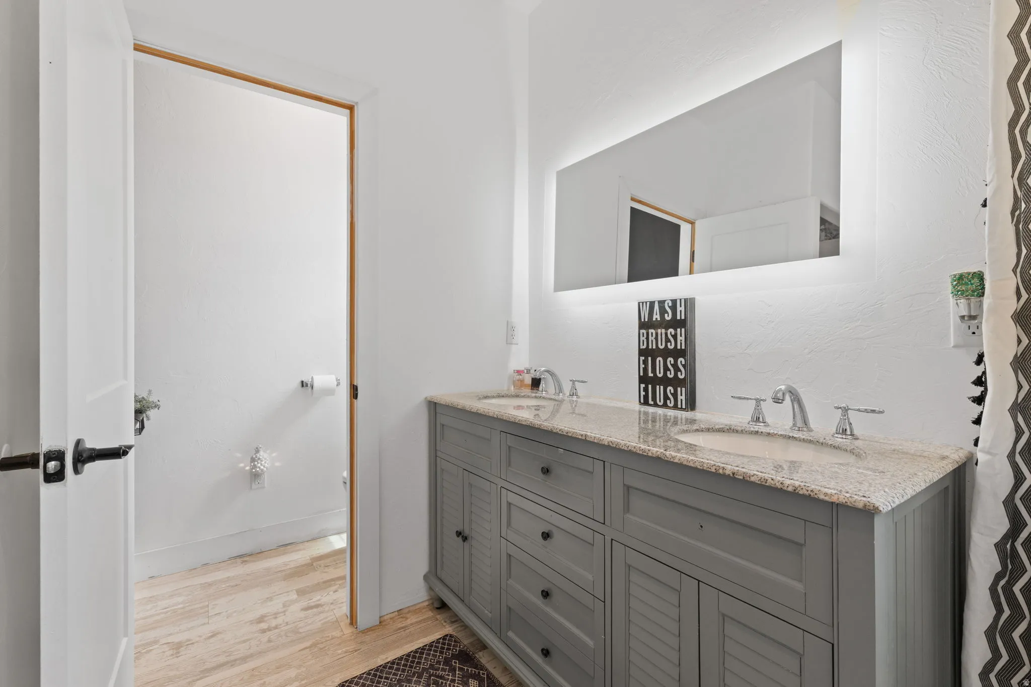 Primary Bedroom with en-suite, bathroom featuring a dual vanity with a light gray cabinet base, granite countertop, and undermount sinks