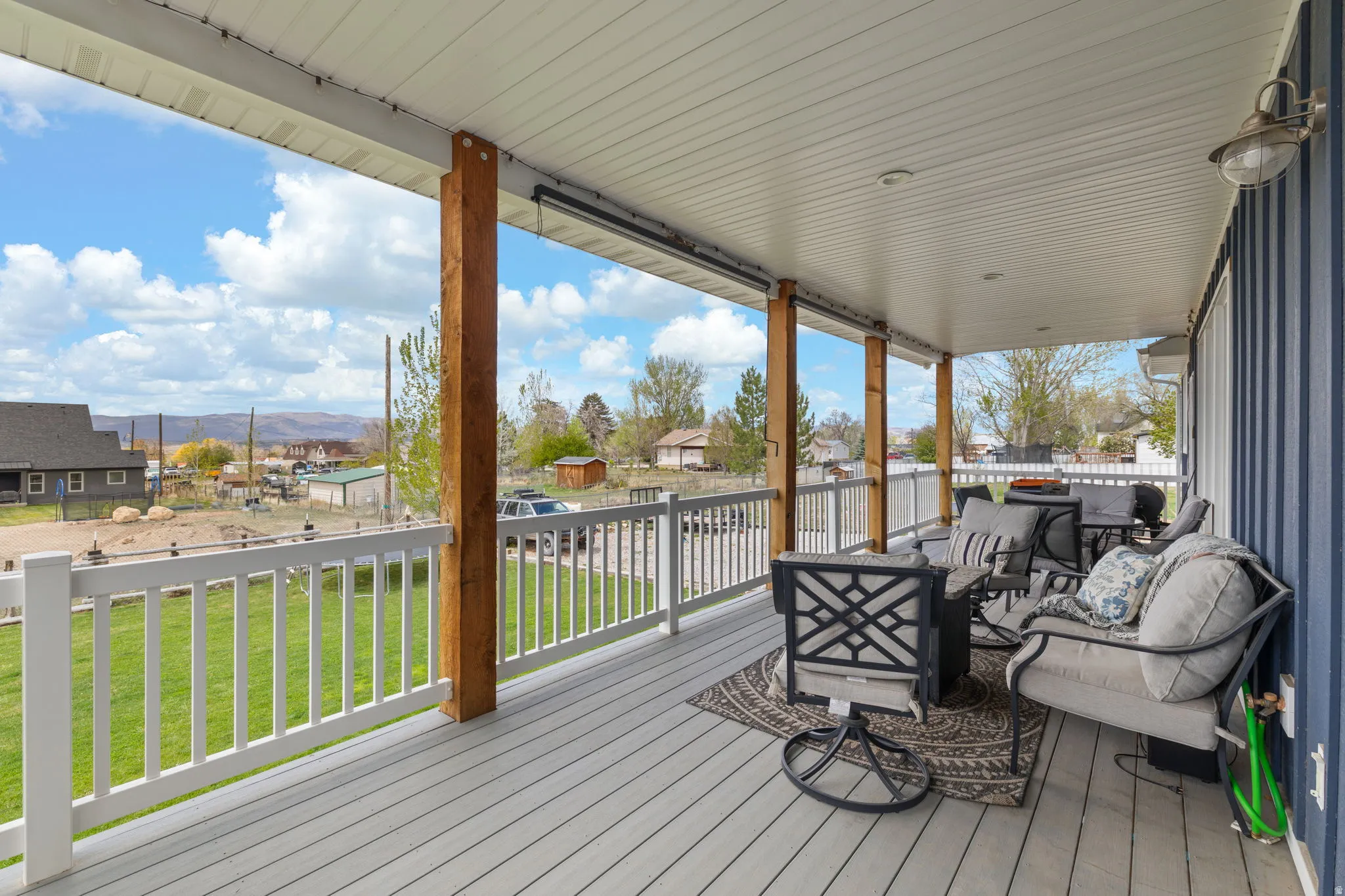 Covered porch featuring a composite deck, white railings, and exposed wood support beams