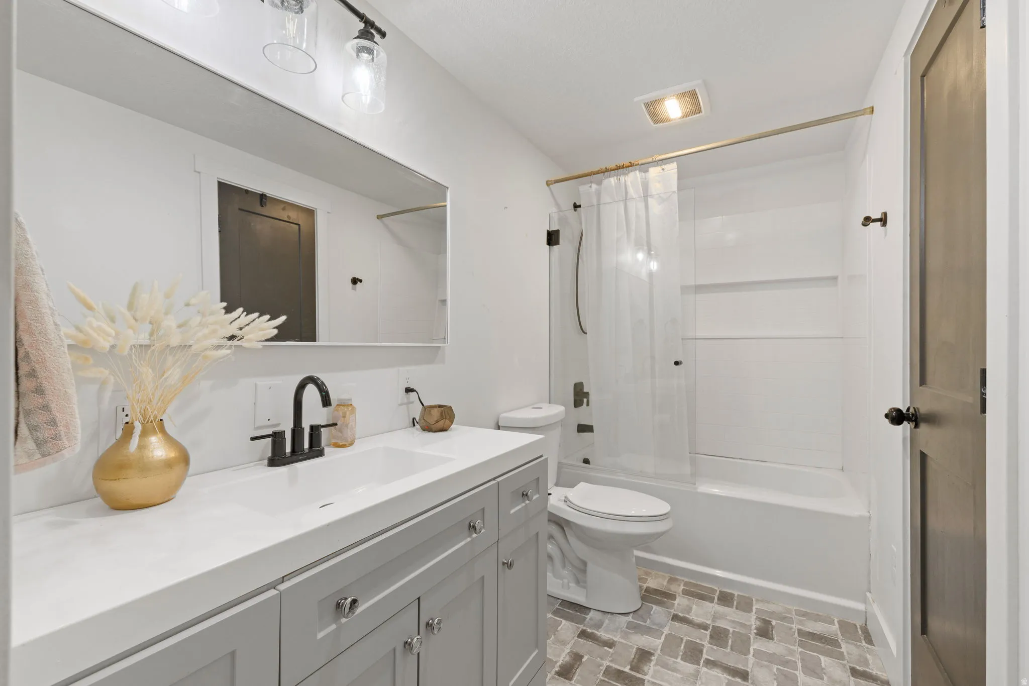 Bathroom featuring a single vanity with light grey cabinetry, a matte black faucet, and a large rectangular mirror