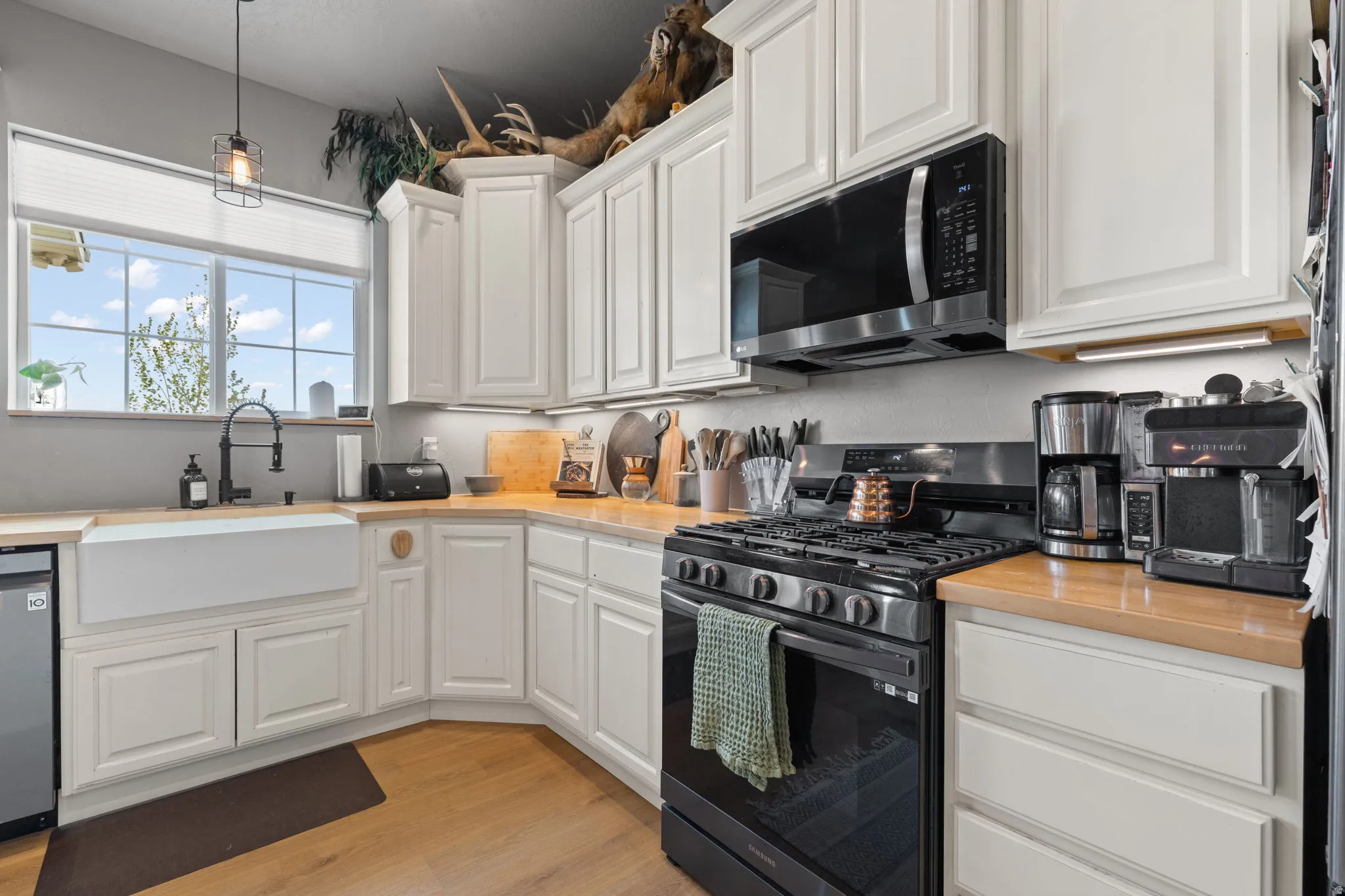 Kitchen featuring light wood-finish countertops, white shaker-style cabinetry, and wood-finish flooring