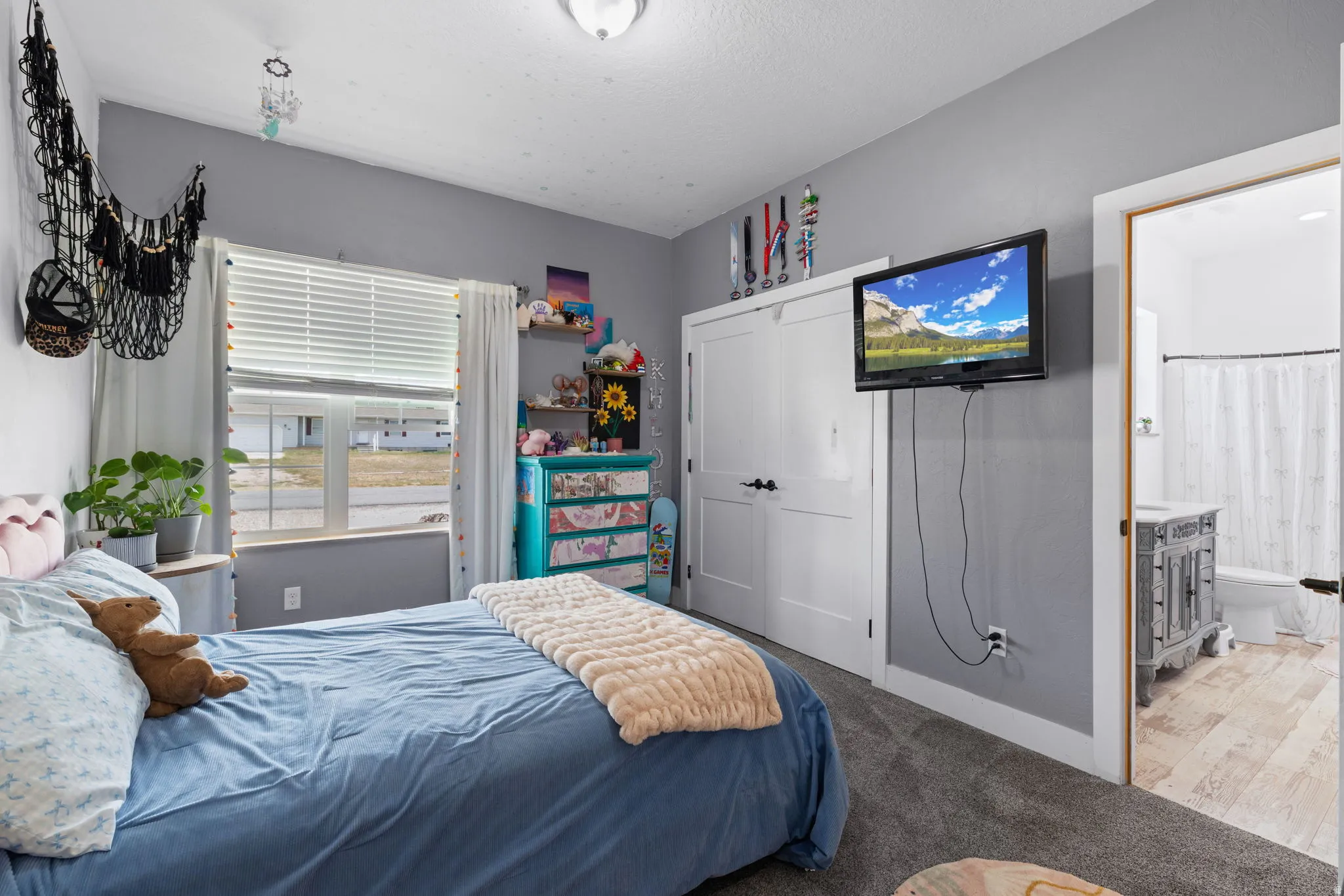 Carpeted bedroom with a window, two white double-panel doors, and a ceiling light fixture