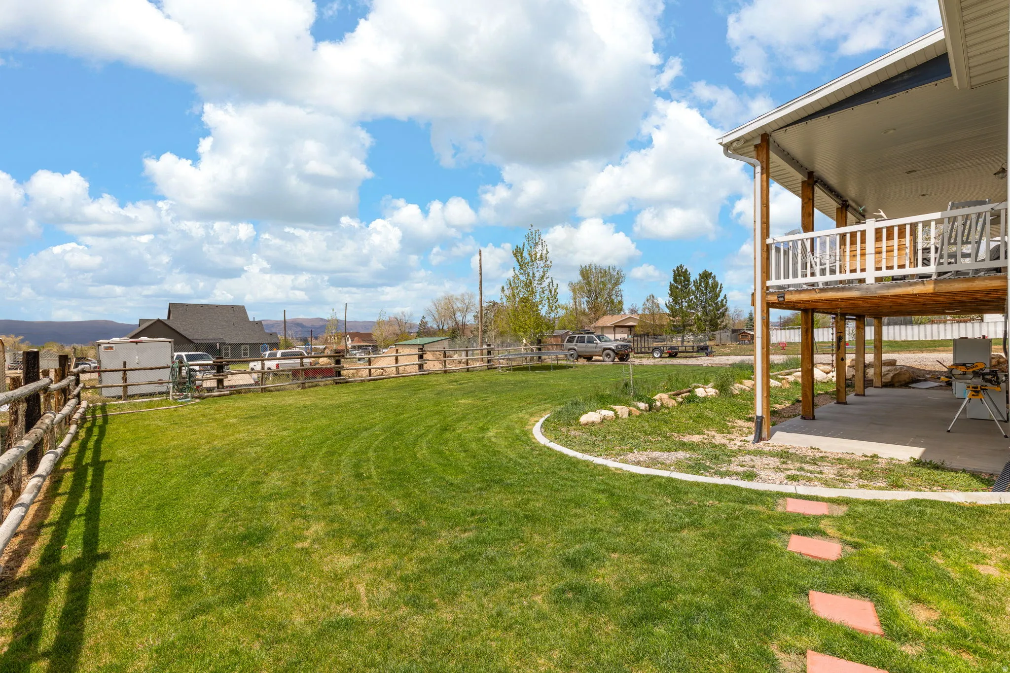 Expansive rear lawn featuring a curved concrete border and stepping stone pathway