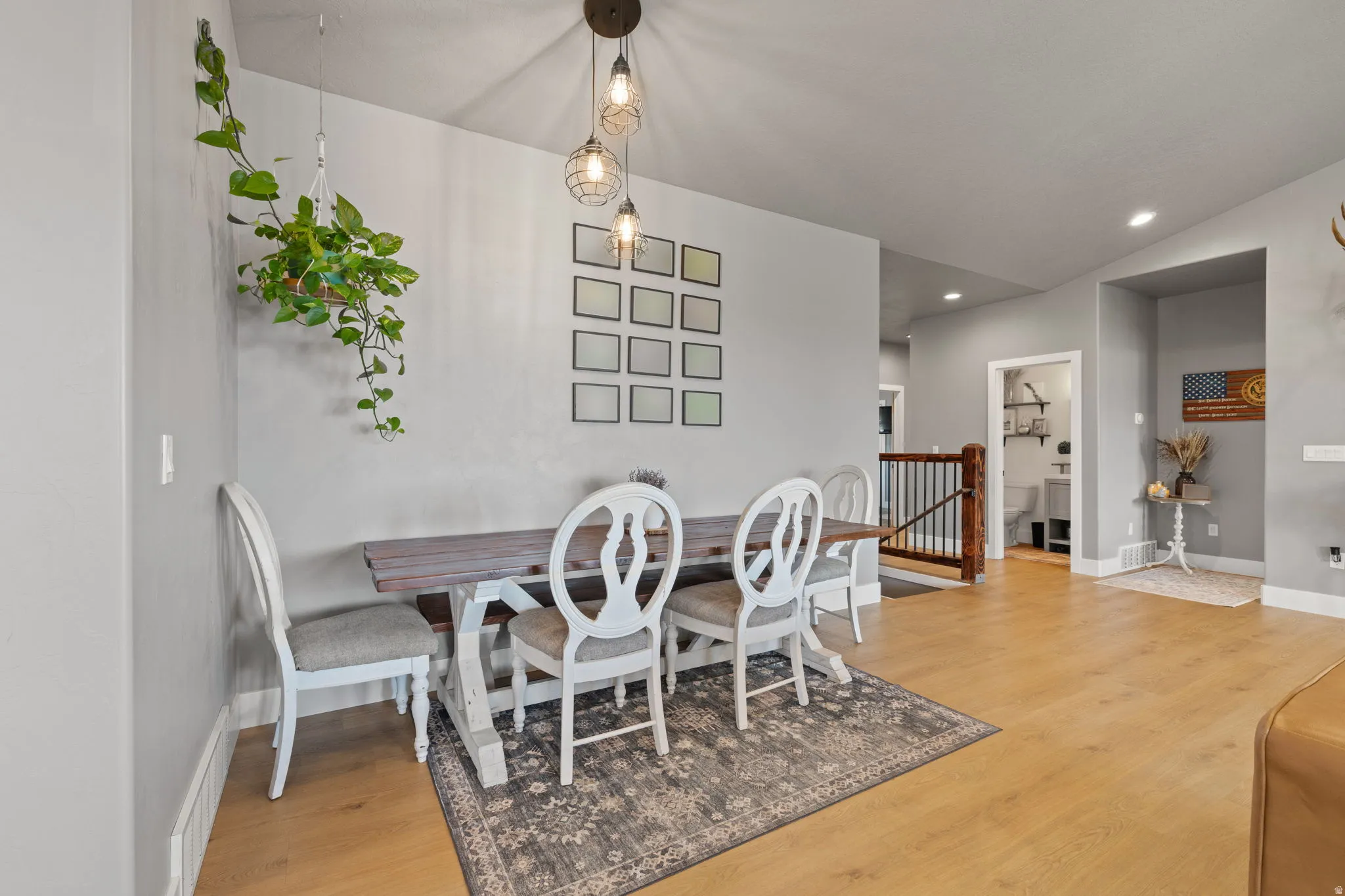 Dining area with light-toned wood-finish flooring, vaulted ceiling, and recessed lighting
