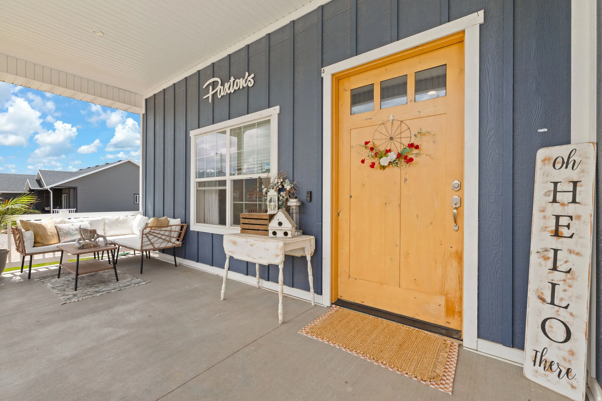 Covered front porch featuring a natural wood-finish, oversized front door with glass transom panels and a wide single window