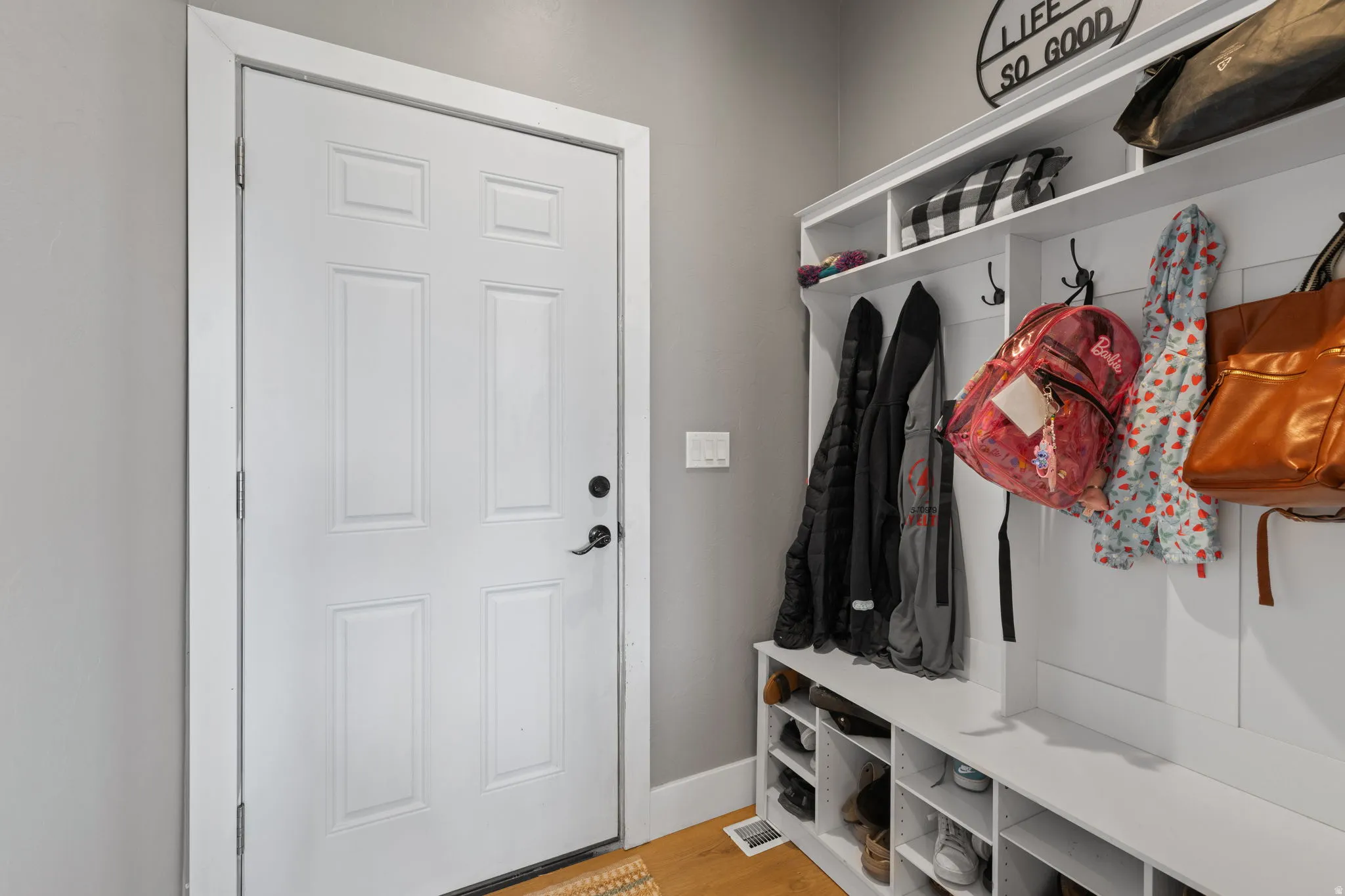 White six-panel door with black hardware, flanked by a built-in mudroom bench with integrated cubbies and upper shelving